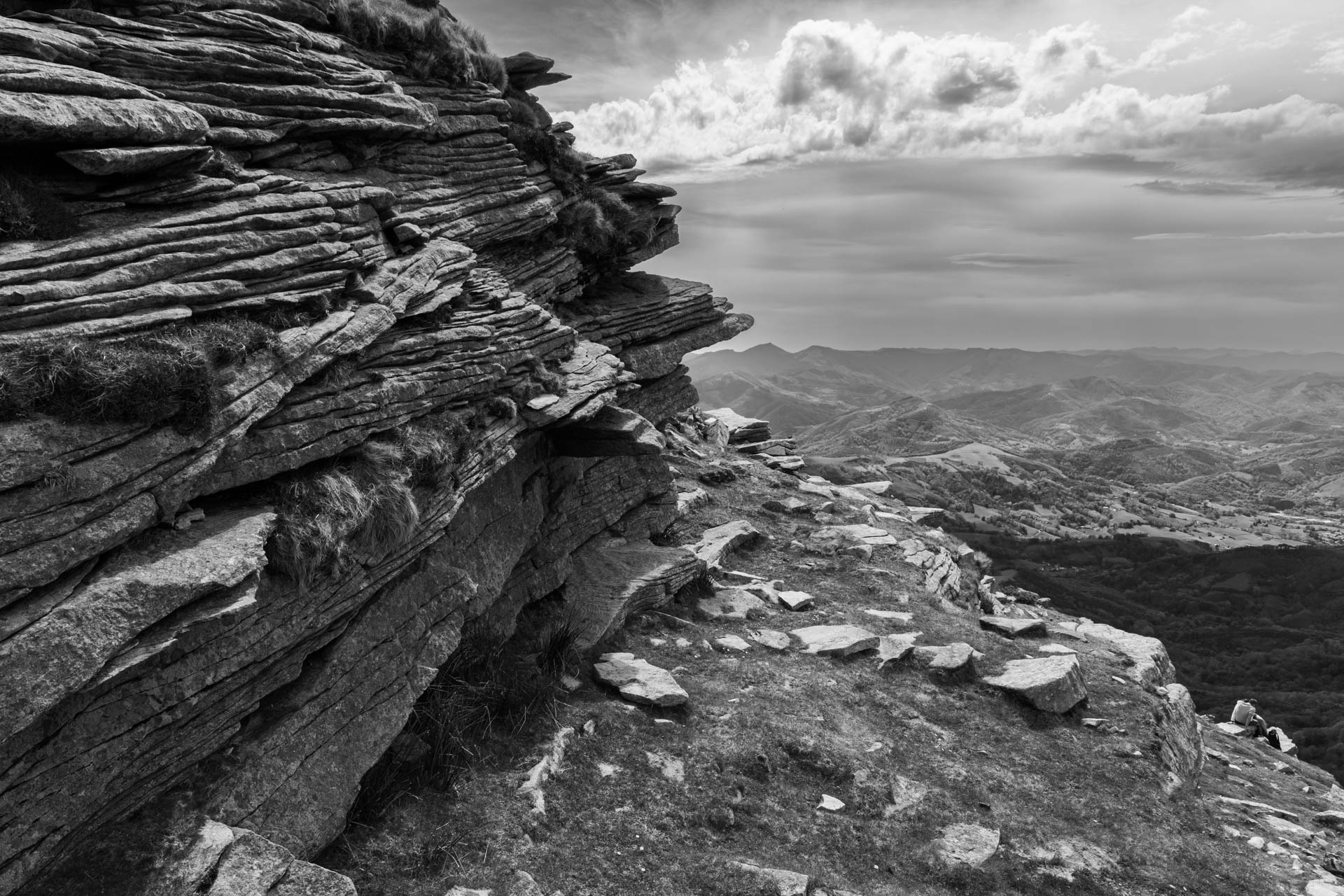 Falaise de roche sédimentaire en surplomb — paysage noir et blanc dramatique